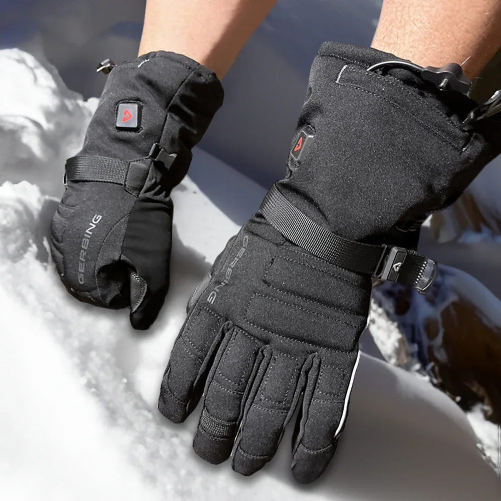 Gerbing S7 Battery Heated Gloves worn in the snow, showing the quilted back panels, wrist cinch strap and heat control button on each gauntlet