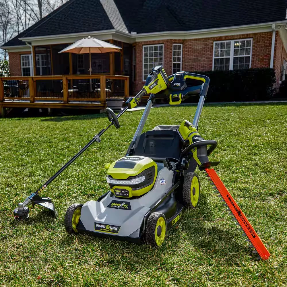 Ryobi 40V HP Hedge Trimmer alongside lawn mower and string trimmer in backyard setting