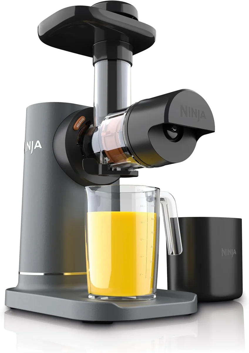Ninja NeverClog Cold Press Juicer JC151 three-quarter view with orange juice in the 24-ounce collection jug and pulp container alongside