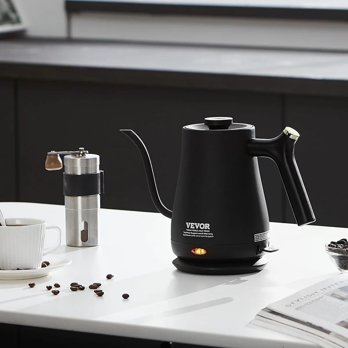 Vevor Gooseneck Kettle on a white counter alongside a manual coffee grinder and scattered coffee beans