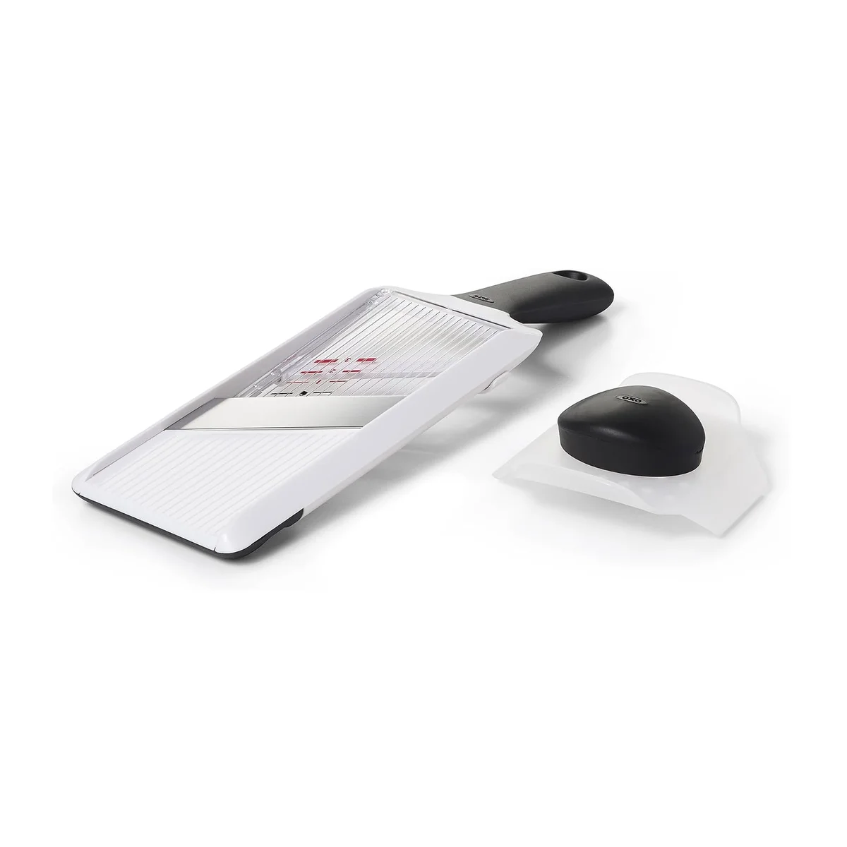 OXO Good Grips Hand-Held Mandoline Slicer angled view with the pronged food holder set beside it, showing the diagonal stainless steel blade and ridged runway