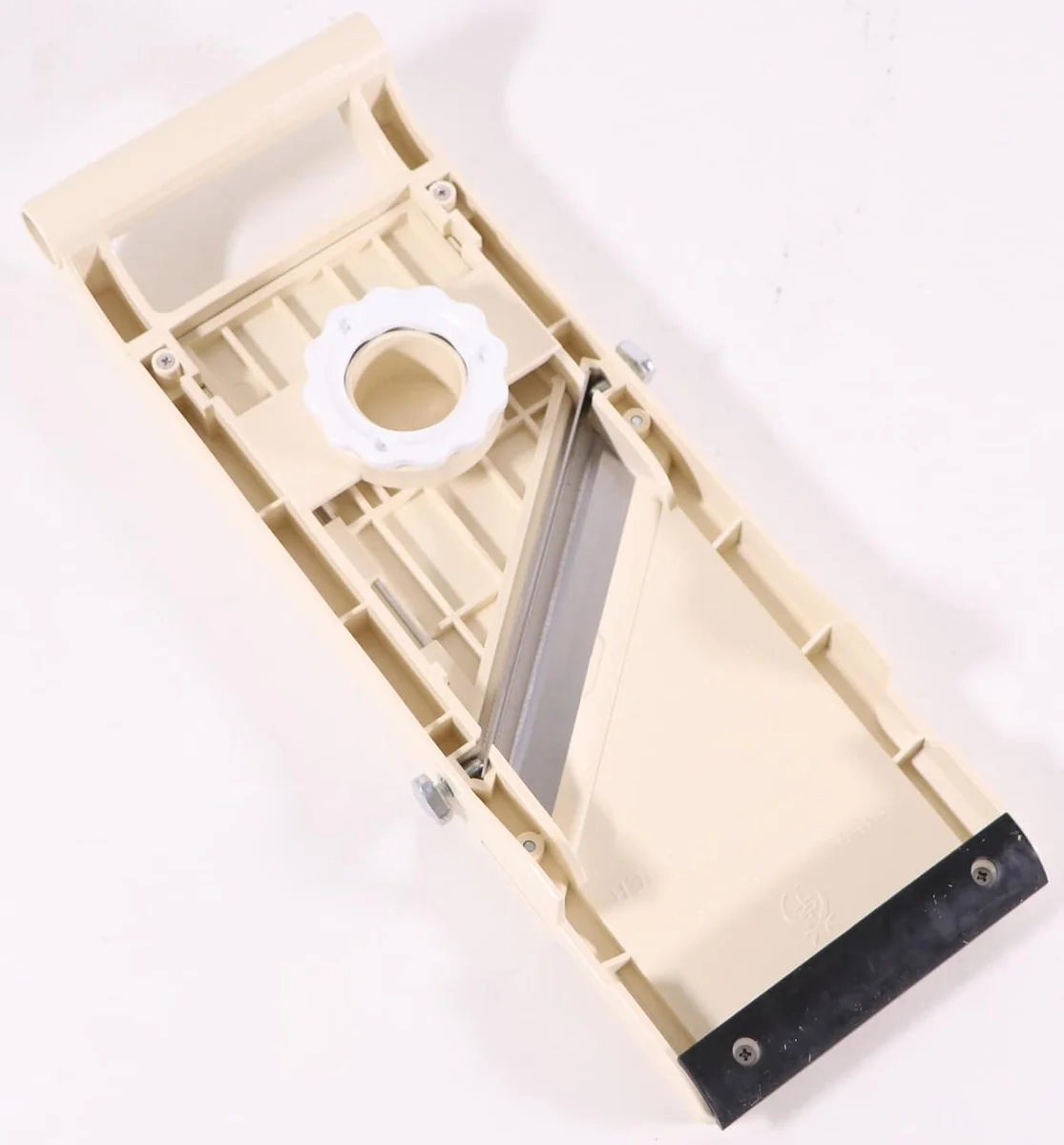 Underside of the beige Super Benriner No. 95 showing the white thickness adjustment dial, the diagonal blade and the black non-slip rubber foot