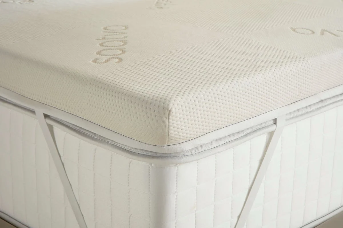 Corner detail of the Saatva Graphite Memory Foam Mattress Topper showing the quilted cover texture and elastic anchor straps