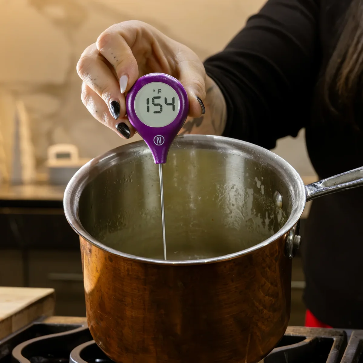 ThermoWorks ThermoPop 2 in purple held over a saucepan, display reading 154 degrees F