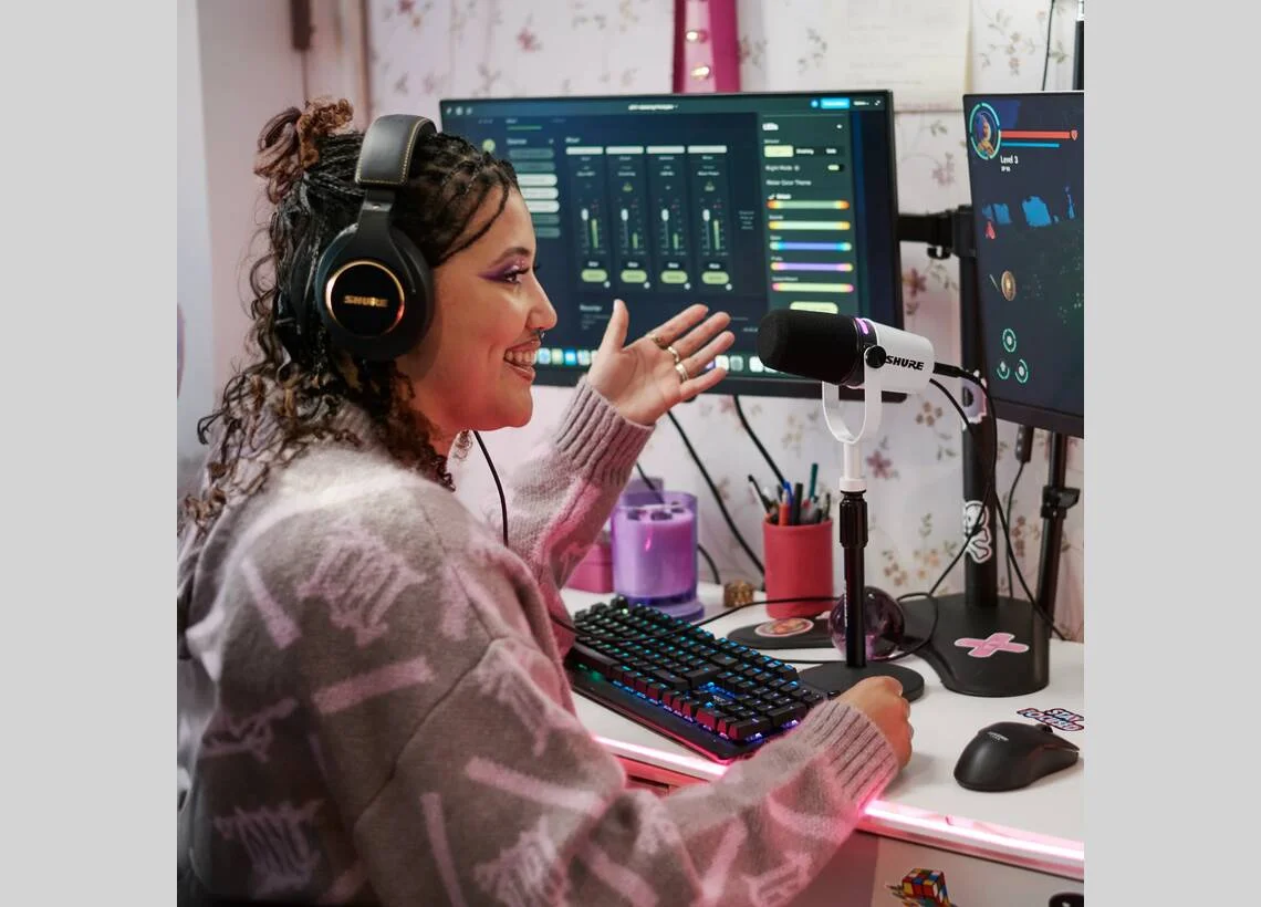Shure MV7+ in use on a streaming desk setup with Shure headphones and dual monitors