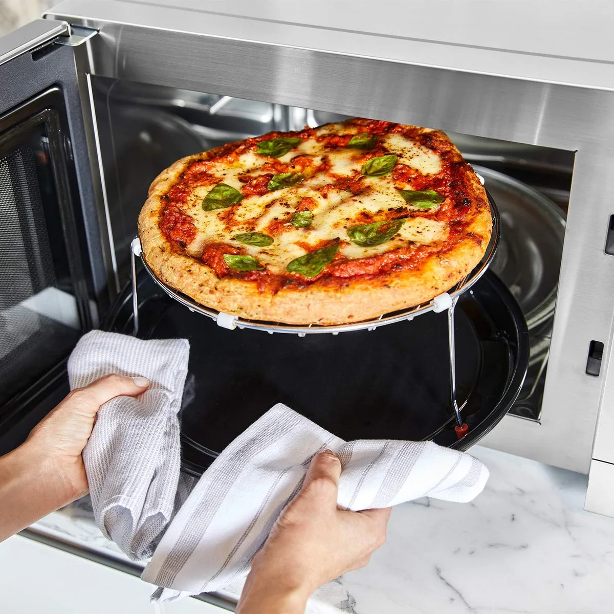 Panasonic HomeChef 4-in-1 interior rack with pizza being removed using oven mitts