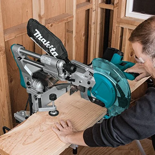Makita LS1019L miter saw in use cutting lumber in a wood-frame workshop