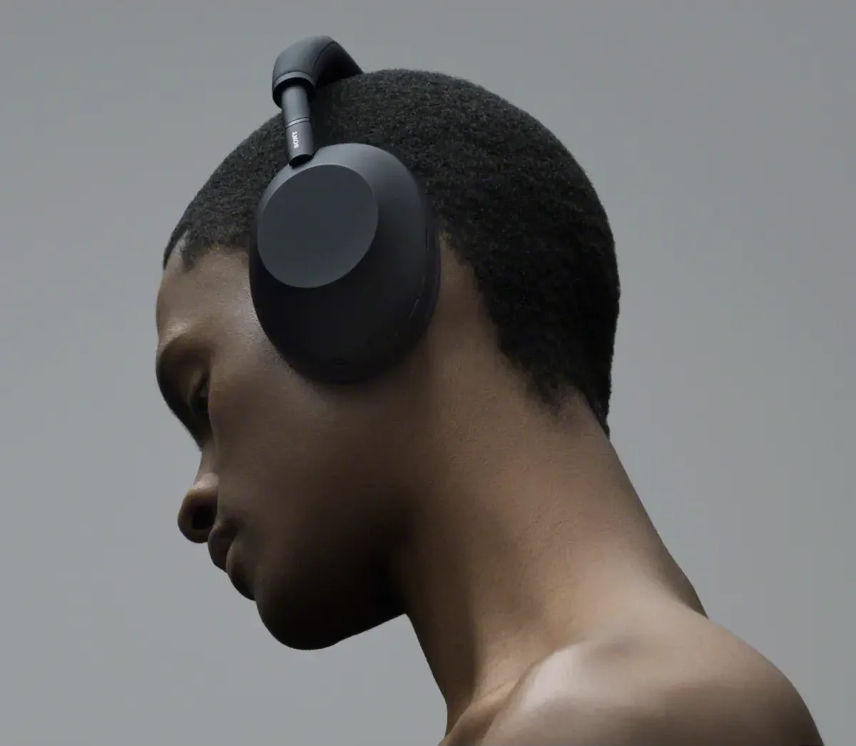 Profile view of a person wearing the Sony WH-1000XM6 in Black against a grey backdrop