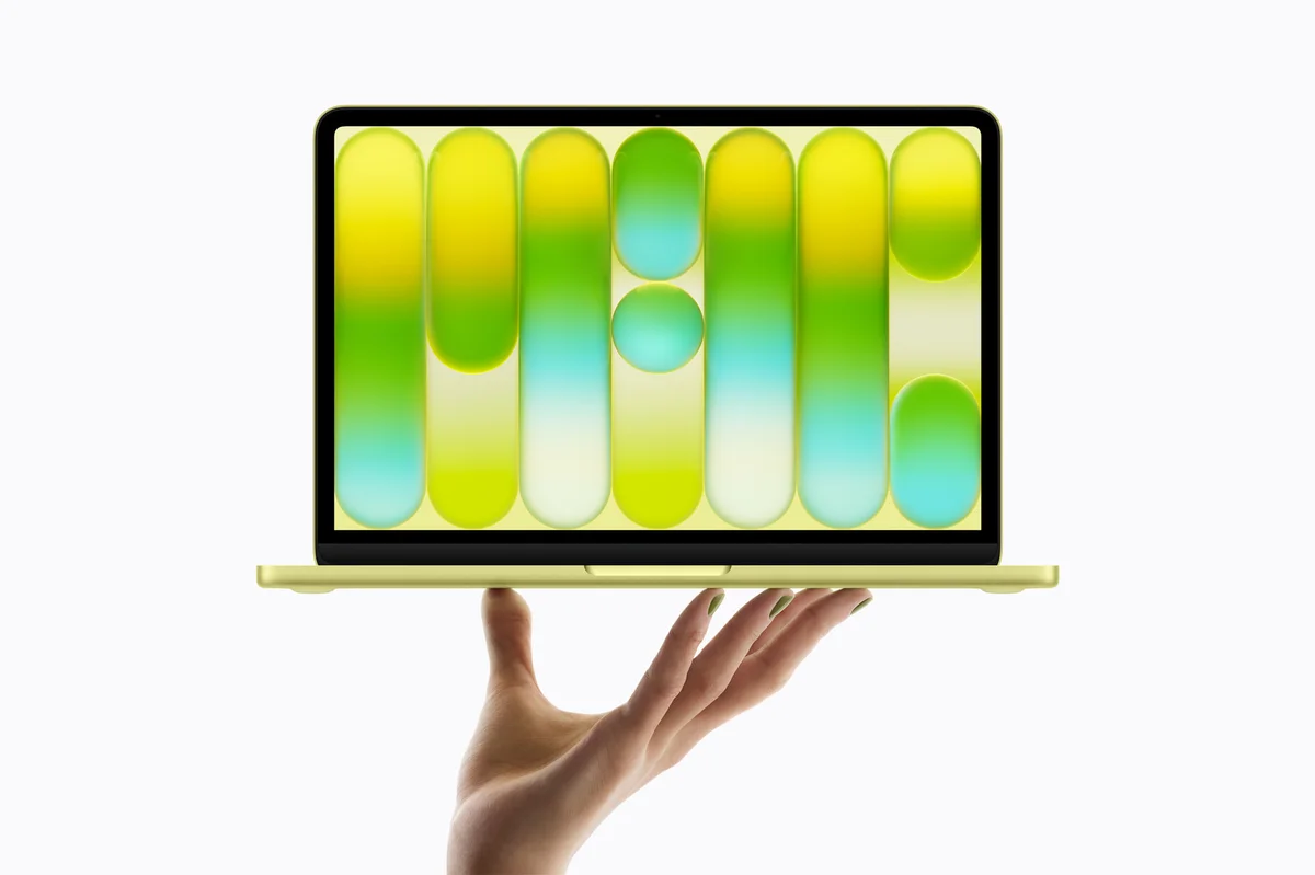 Apple MacBook Neo in Citrus held open on one hand, showing how thin and light the 13-inch laptop is
