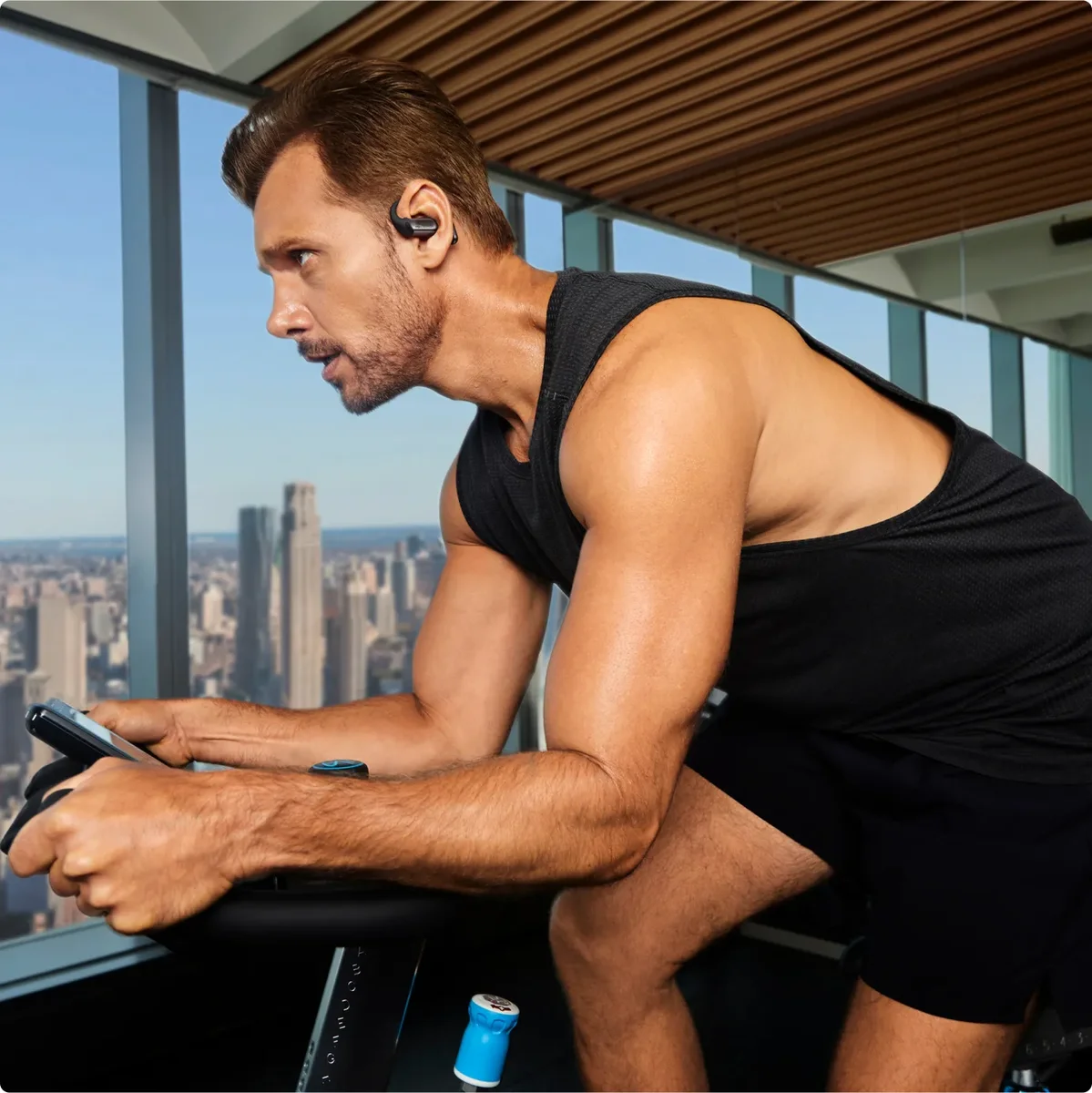 Man wearing a Shokz OpenFit Pro earbud on his ear while cycling