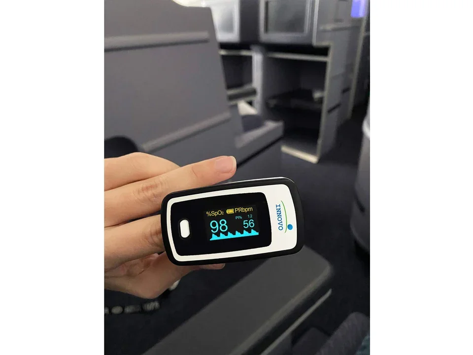 Innovo Deluxe iP900AP held in hand in use, showing the color OLED readout of SpO2 and pulse rate