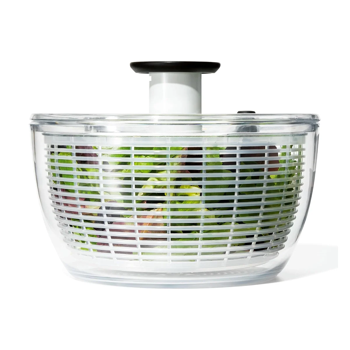 OXO Good Grips Salad Spinner (large 6.22 qt, white) front view with clear bowl, white basket filled with mixed greens, and black pump knob raised