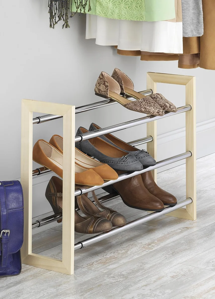 Whitmor 3 Tier Expandable Shoe Rack in a closet holding flats, heels and loafers beneath hanging clothes