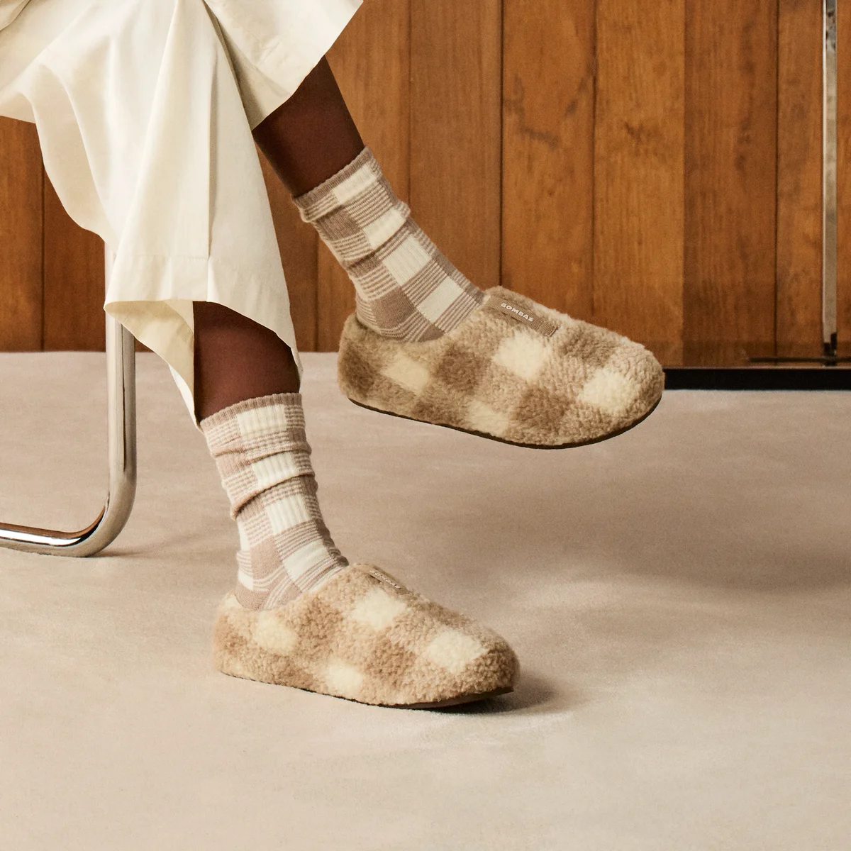 Bombas Sunday Slipper worn on-foot with matching checkerboard socks in a cozy interior, showing the fit and open-heel silhouette