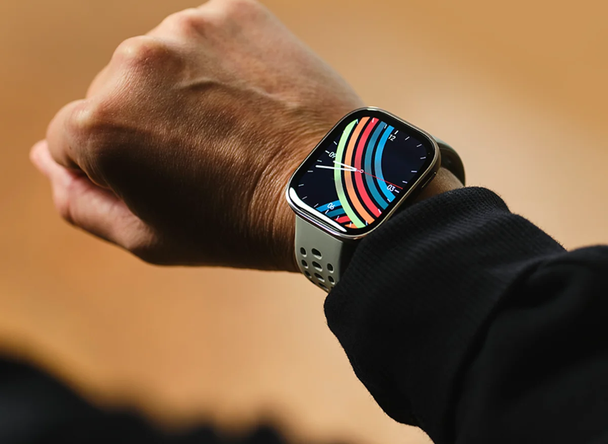 Amazfit Bip 6 worn on a wrist, lifestyle shot showing the watch raised toward the viewer with the AMOLED watch face lit