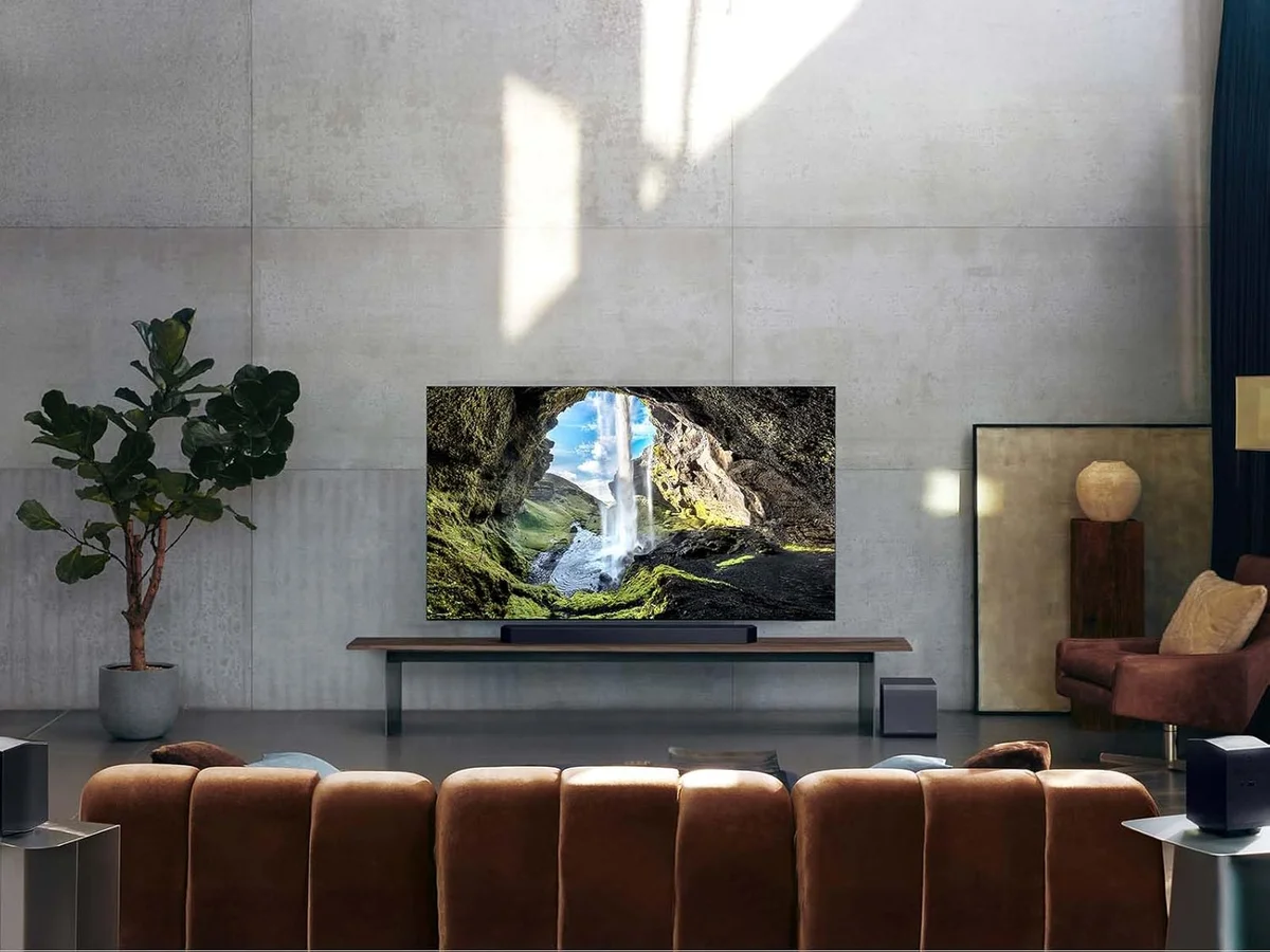 Samsung HW-Q990F system in a modern living room with soundbar under TV, subwoofer and rear speakers placed around sofa