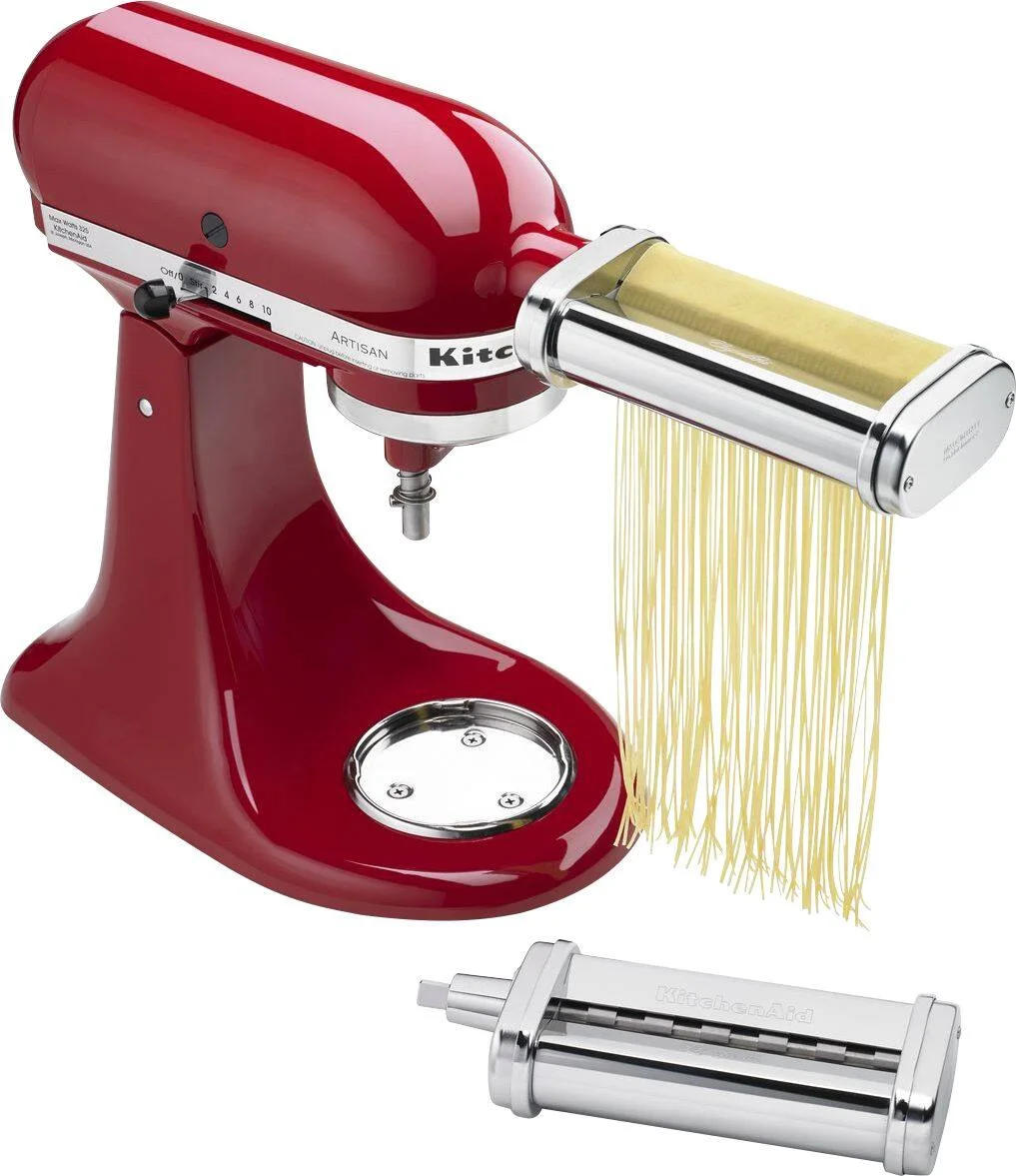 KitchenAid Artisan mixer with spaghetti cutter attachment producing fresh pasta strands on white background