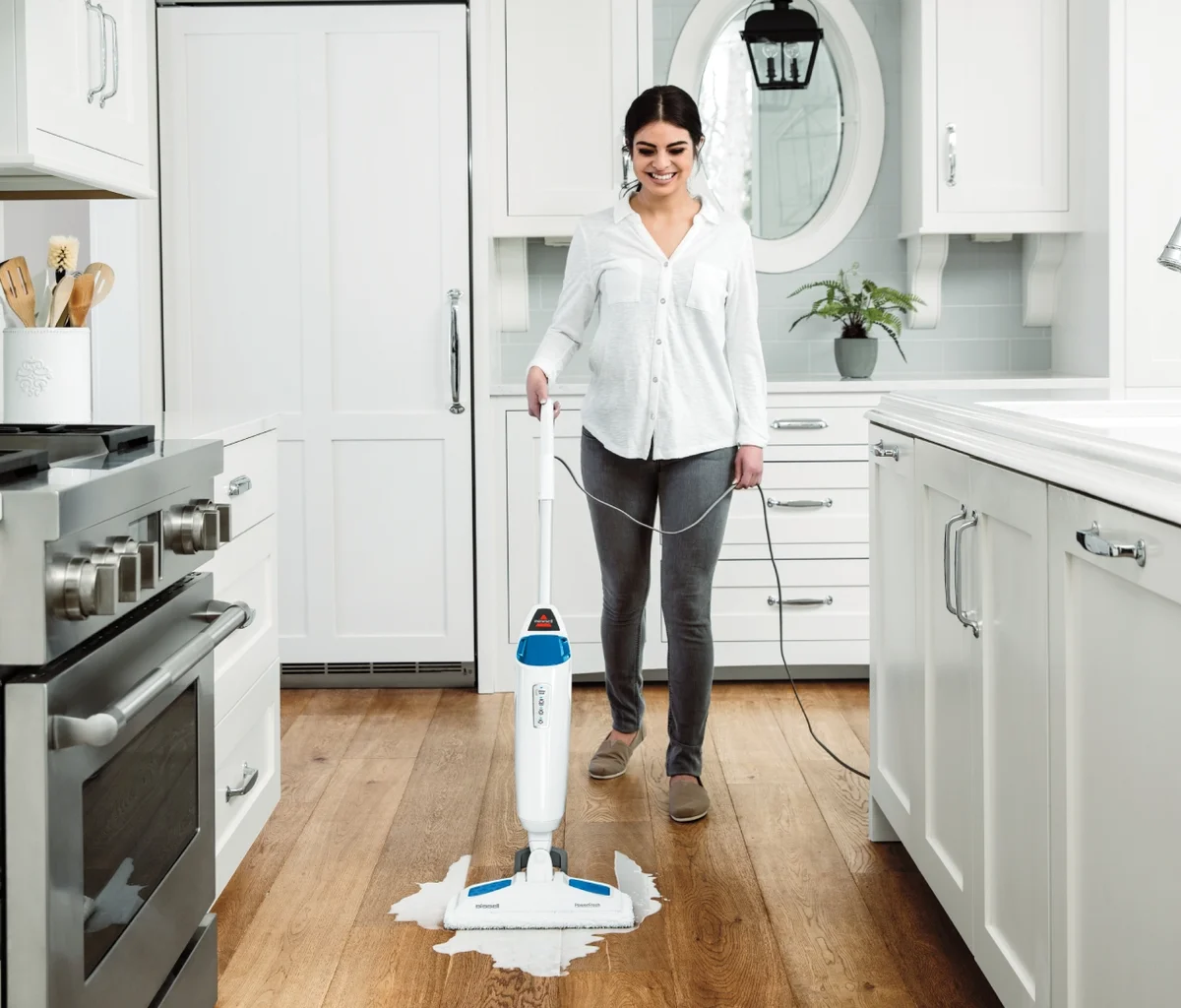 Woman using Bissell PowerFresh 1940A steam mop on hardwood floor in kitchen