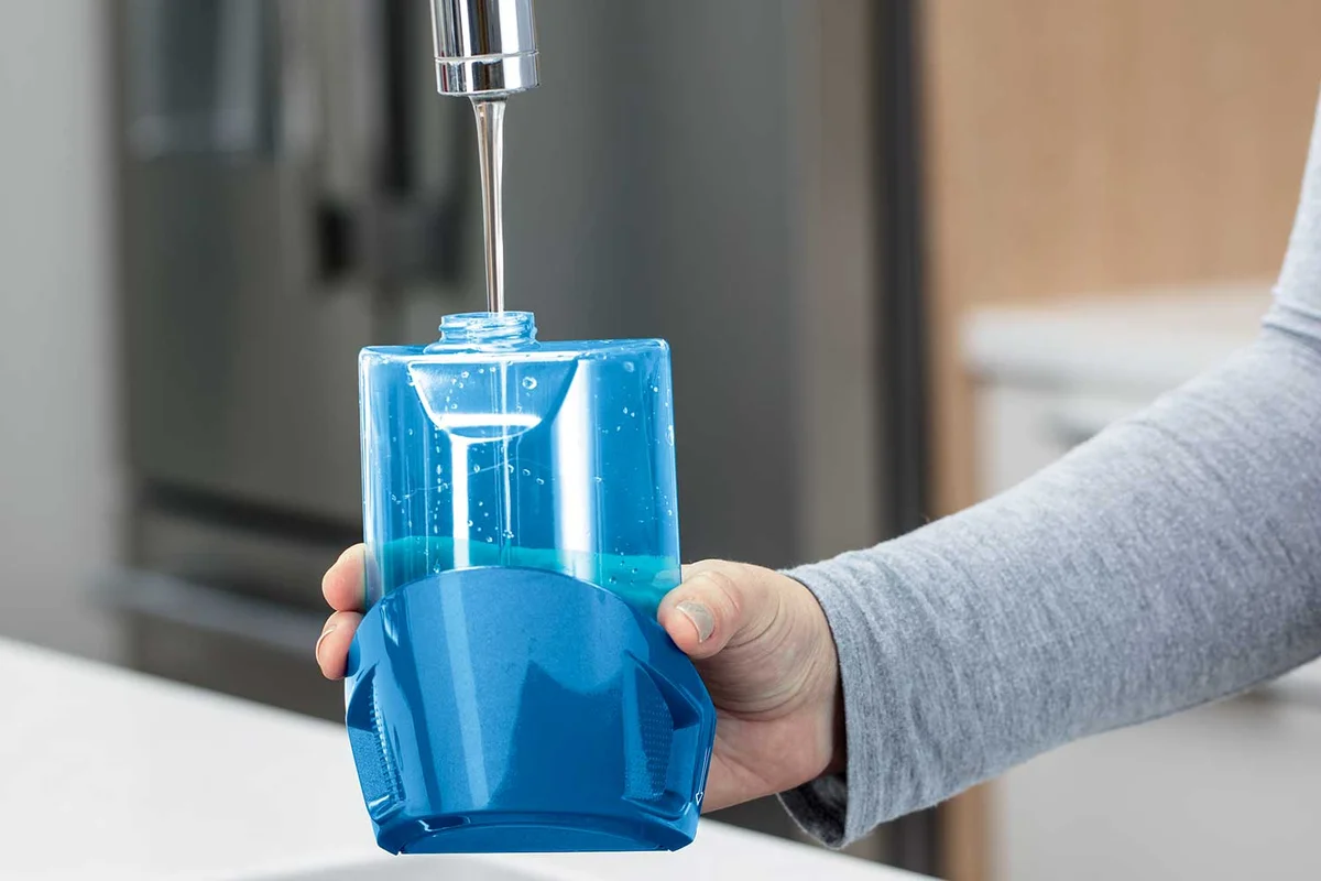 Bissell PowerFresh 1940A removable water tank being filled at a kitchen faucet
