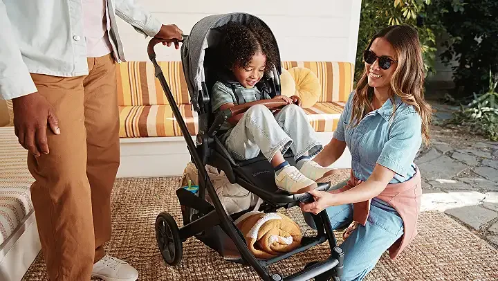 UPPAbaby Cruz V3 with toddler seated outdoors, parent kneeling beside stroller