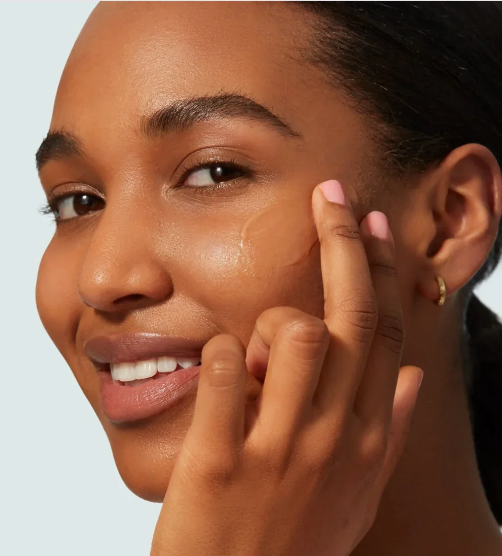 Model applying Supergoop! Unseen Sunscreen to cheek showing invisible finish