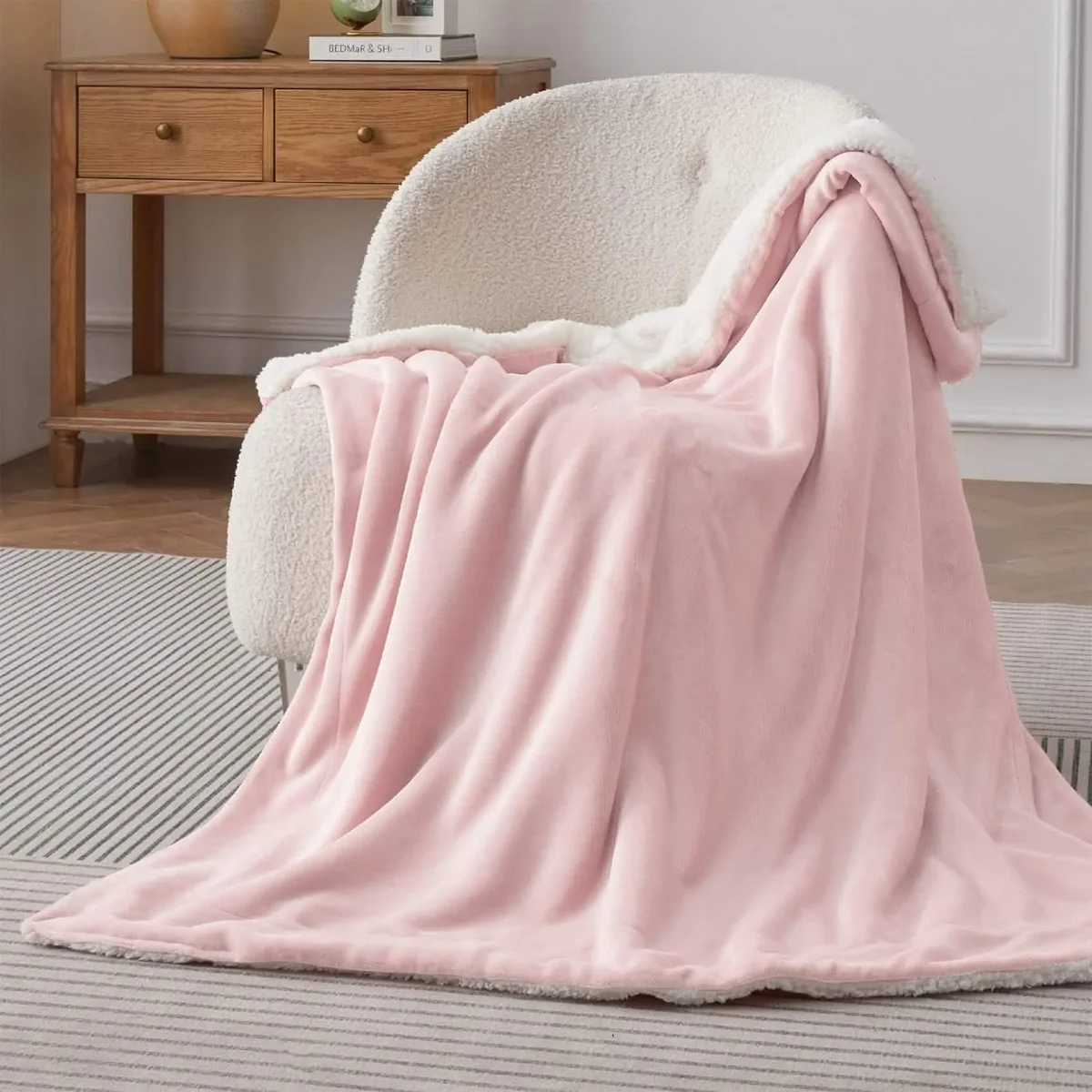 Bedsure Sherpa Fleece Throw in pink draped over an accent chair showing full drape and sherpa lining