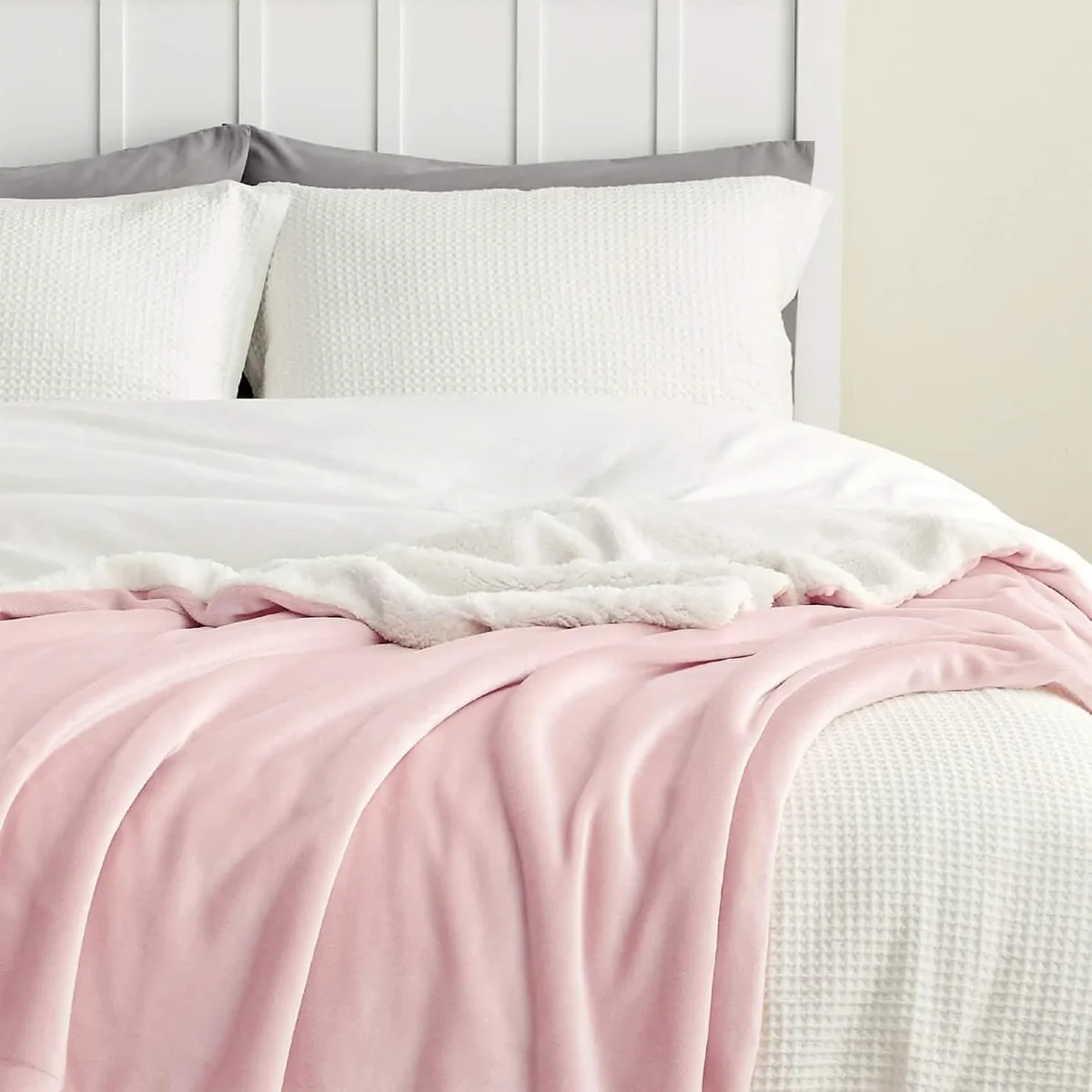 Bedsure Sherpa Fleece Throw in pink layered across a made bed in a bedroom setting