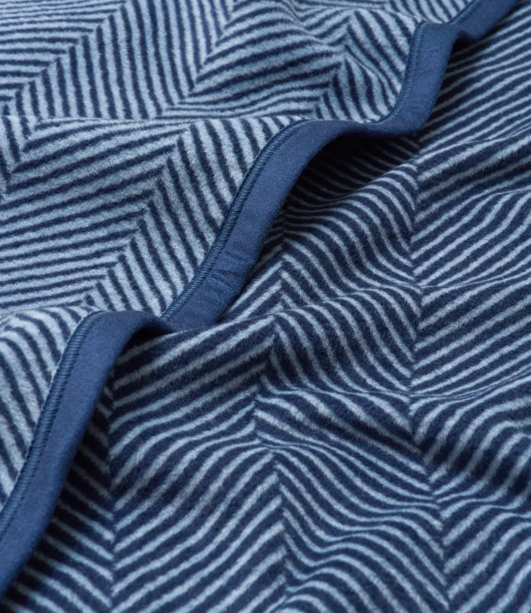 Close-up of the ChappyWrap Harborview Herringbone blanket's woven herringbone texture and navy binding