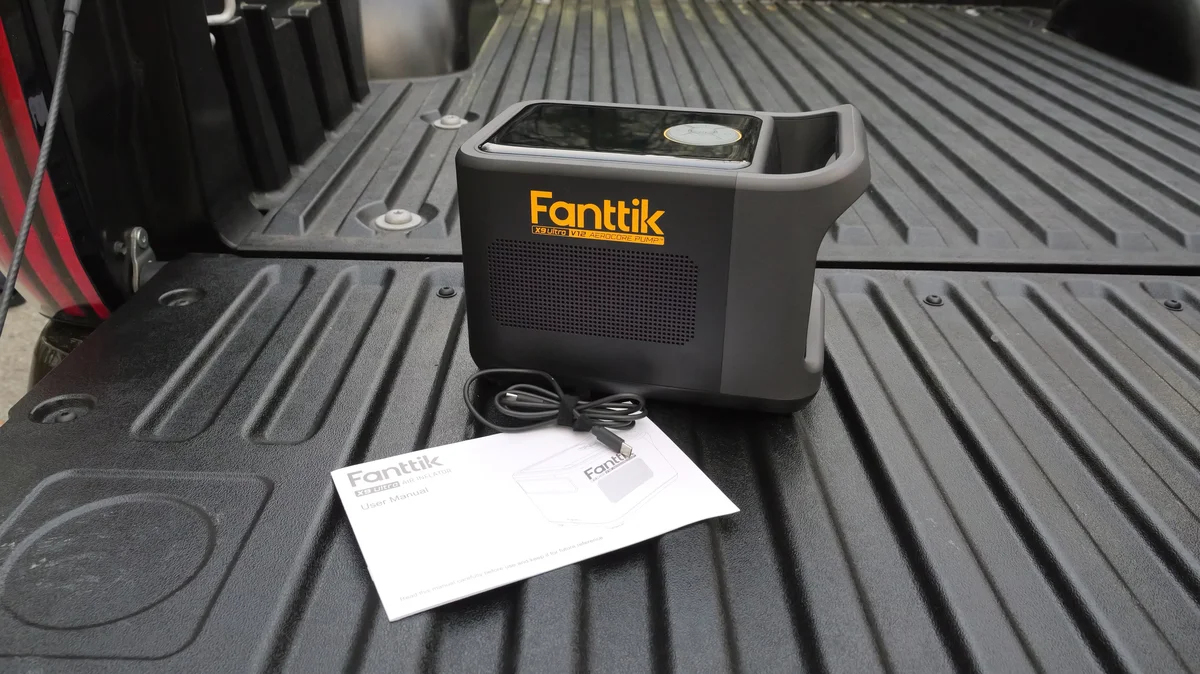 Fanttik X9 Ultra V12 inflator in truck bed with user manual and charging cable