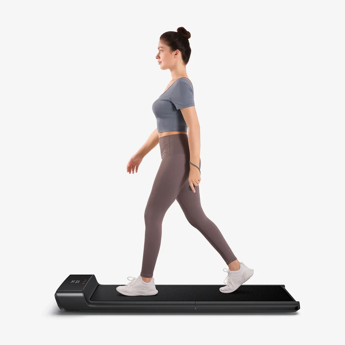 Person walking on WalkingPad A1 Pro treadmill in workout clothing, side profile view