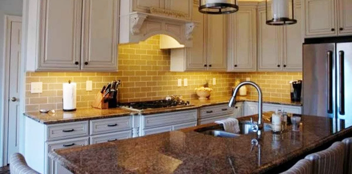 Litever light bars casting warm white light across a granite kitchen counter and subway tile backsplash