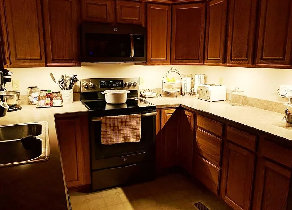 Wobane under cabinet LED strip lights casting warm white light across a wood-cabinet kitchen countertop