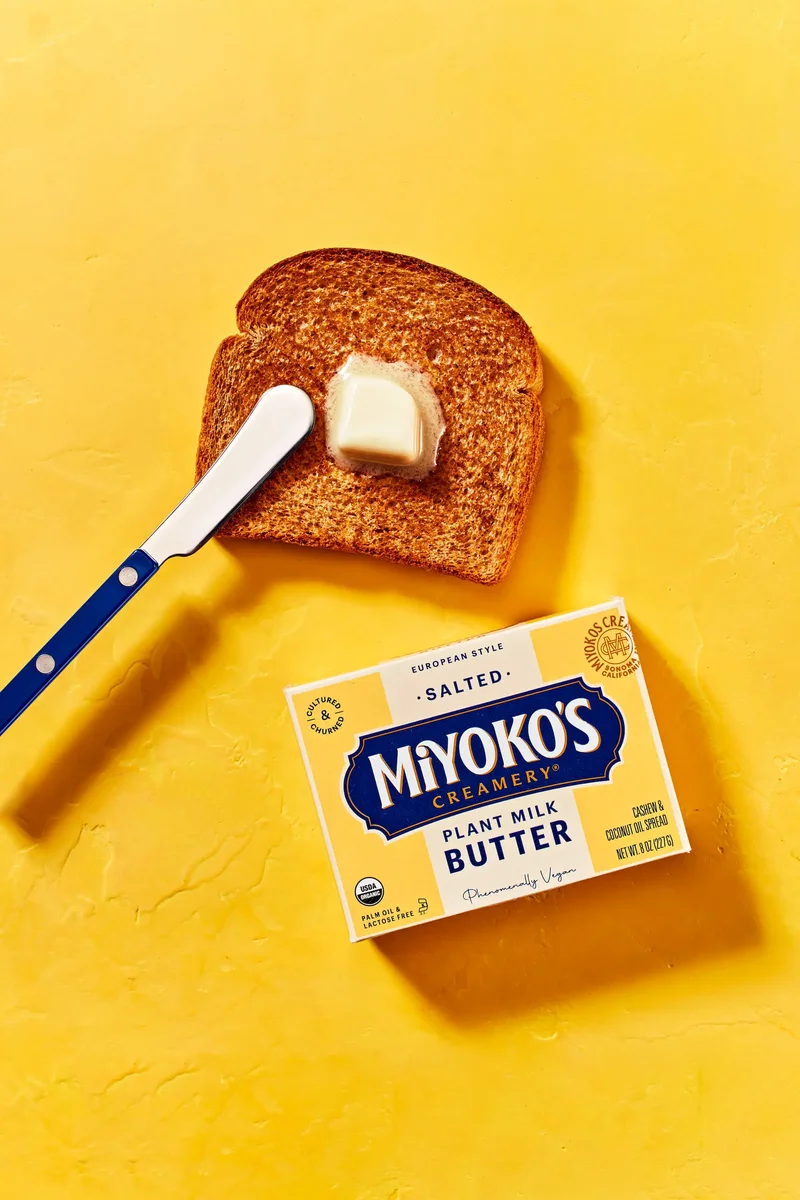 Miyoko's Creamery vegan butter with toast and knife on yellow background