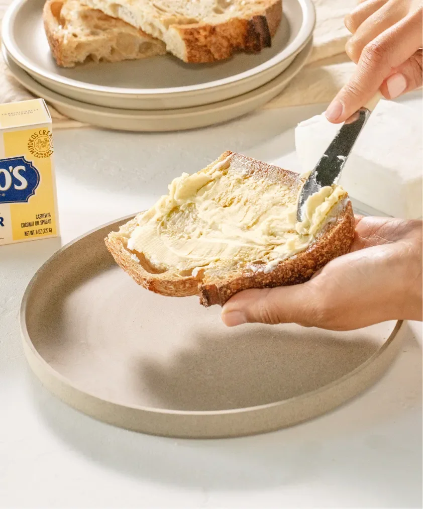 Miyoko's Creamery vegan butter being spread onto sourdough toast