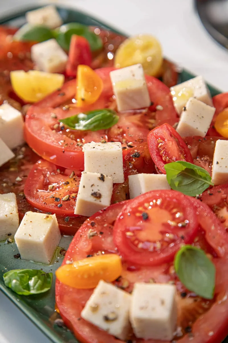 Miyoko's fresh mozzarella cubed in a caprese salad with heirloom tomatoes and basil