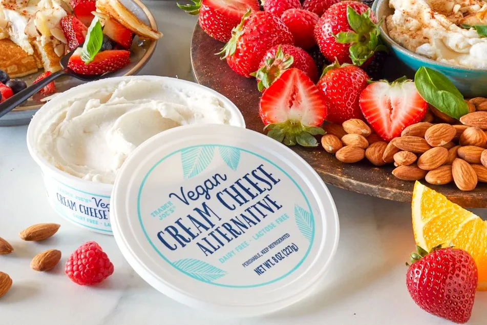 Trader Joe's Vegan Cream Cheese Alternative tub opened on a marble surface surrounded by strawberries, almonds, and raspberries