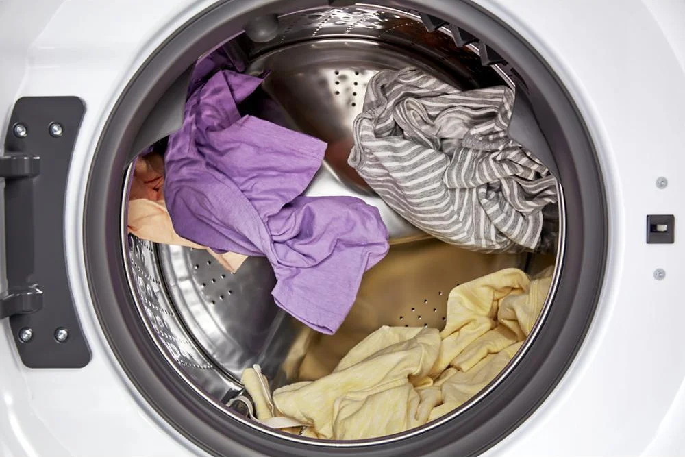 Whirlpool All-in-One washer-dryer open drum showing large stainless steel interior with laundry