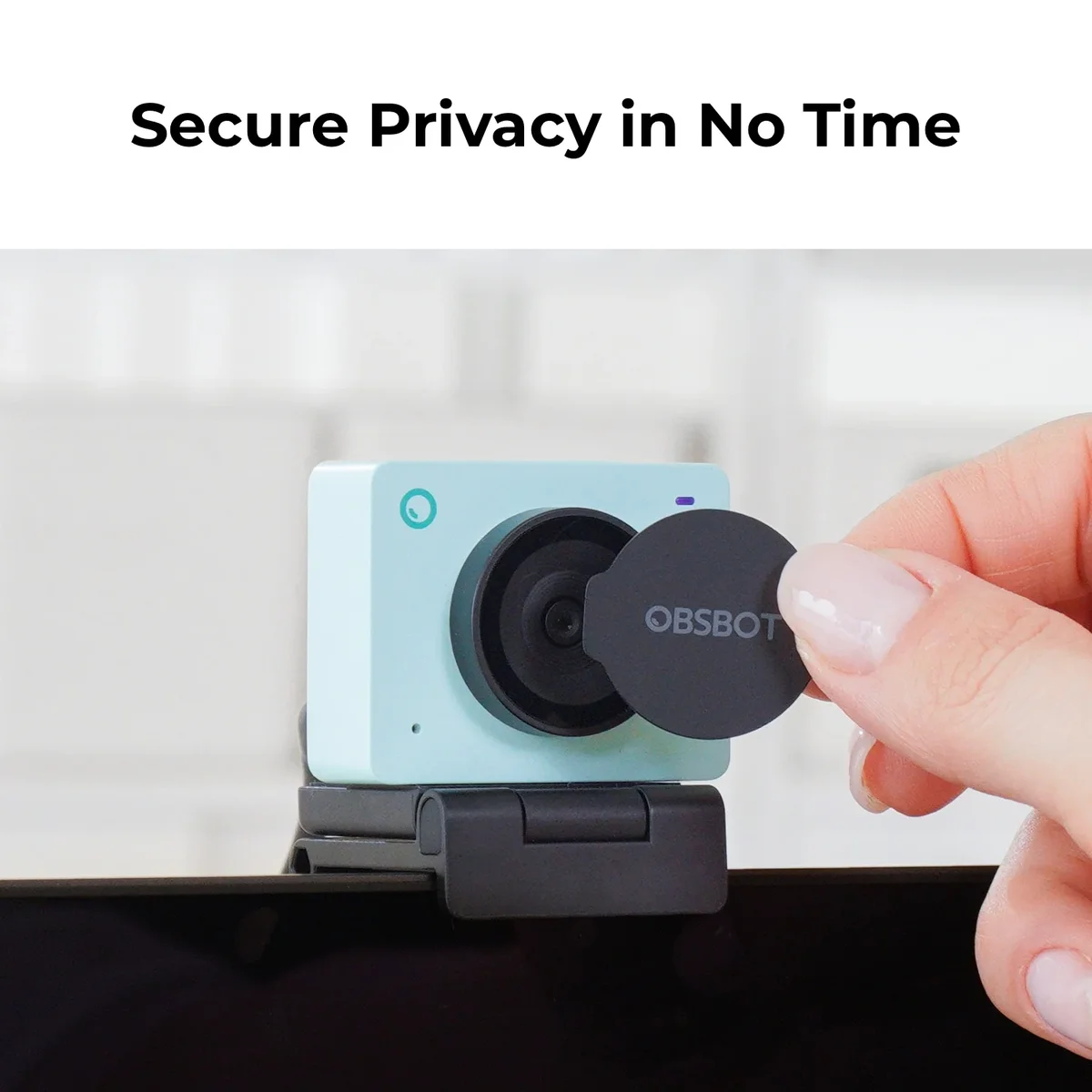 OBSBOT Meet SE webcam mounted on a monitor with privacy lens cover being attached