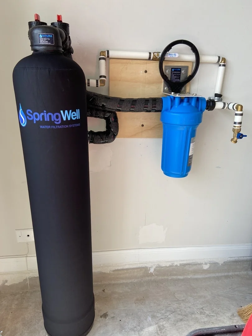 SpringWell CF1 whole house water filter system installed in a garage with blue sediment pre-filter
